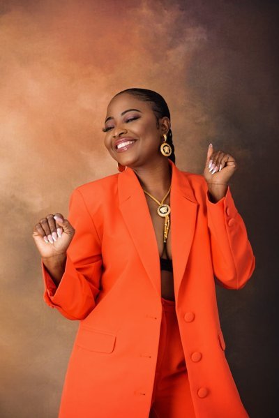 Woman in an orange suit dancing joyfully during a studio birthday photoshoot in Nottingham.